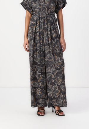 Maxi dress in dark fabric with floral pattern in cream, orange, and grey. Features loose sleeves and an elastic waist. Paired with black heeled sandals.