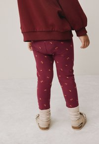 Bordo legice s češnjevim vzorcem, iz mehkega bombažnega materiala, ozkega kroja, kombinirane z bež čevlji in kremnimi gležnjčnimi nogavicami.