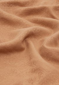 Tessuto testurizzato in un caldo colore terracotta, caratterizzato da un motivo sottile con dettagli fini. Morbido e con caduta fluida.