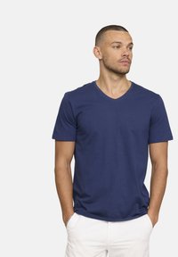 T-shirt bleu marine à col en V en coton, à manches courtes, coupe ajustée, offrant une texture lisse et un design minimal sans motifs ni accents.