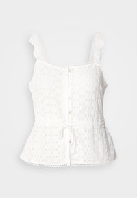 White lace top with scalloped straps, button front closure, peplum hem, and adjustable tie at the waist. Delicate floral pattern throughout.