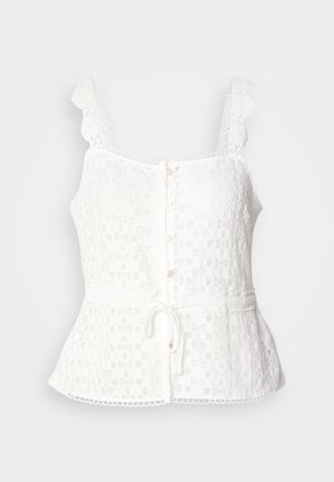 White lace top with scalloped straps, button front closure, peplum hem, and adjustable tie at the waist. Delicate floral pattern throughout.