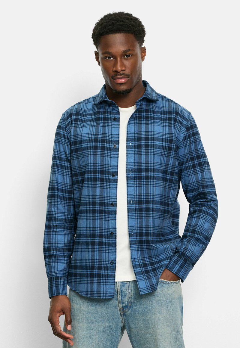 Blaue und schwarze kariertes Hemd aus Flanell, mit Knöpfen, Kragen und langen Ärmeln, über einem weißen T-Shirt getragen.