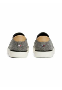 Gray canvas slip-on shoes with a beige heel accent and a white rubber sole. Features a small logo by the heel. Flat design, no laces.
