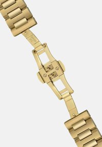 Złota metalowa bransoletka zegarka z diamentowym wzorem. Charakteryzuje się polerowanym wykończeniem i mechanizmem zapięcia. Gładka tekstura z zaokrąglonymi krawędziami.