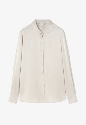 Blusa de manga larga color beige con cuello puntiagudo, cierre frontal de botones y textura lisa. Los puños tienen un detalle de botón, ofreciendo un diseño clásico.