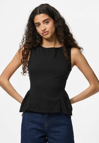Crni peplum top s glatkom teksturom, sa okruglim izrezom i bez rukava, u kombinaciji s tamnim trapericama.