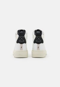 High-top sneakers with white leather upper, black and pale pink accents, padded collar, and textured rubber sole.