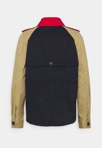 Farbblockierte Jacke mit einem roten Kragen, schwarzem Körper und beige-farbenen Ärmeln. Beinhaltet eine Rückenklappe mit einem Knopfverschluss und einem schlanken Design.
