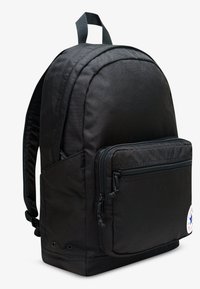 Černý batoh z odolné látky s oblým tvarem, přední kapsou na zip a nastavitelnými polstrovanými popruhy.