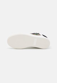 Vita sneakers med en texturerad gummisula, prydda med färgglada pärlor och paljetter på ovandelen. Platta snören och en stilren design.