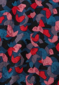 Motif abstrait de formes irrégulières rouges, roses, bleues, violettes et noires sur fond de tissu texturé.