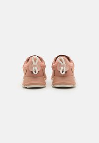 Baskets de sport roses avec une finition texturée, présentant un design bicolore, des semelles en caoutchouc et des poignées blanches distinctives au talon.