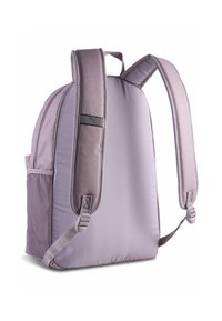 Mochila de tela morada con forma acolchada, correas ajustables, bolsillo lateral de malla y detalle de logo sutil en la correa. Textura suave.