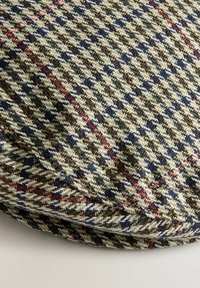 Villa kangasta houndstooth-kuvioissa, jossa on vihreitä, ruskeita, laivastonsinisiä ja punaisia sävyjä. Tekstuuria on kudottu ja se on hieman koholla.