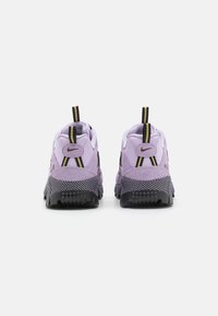 Lila Nike Air-sneakers med en texturerad yta, svarta mesh-accenter och gula snören. Har en vadderad vrist och ett mönstrat sula.