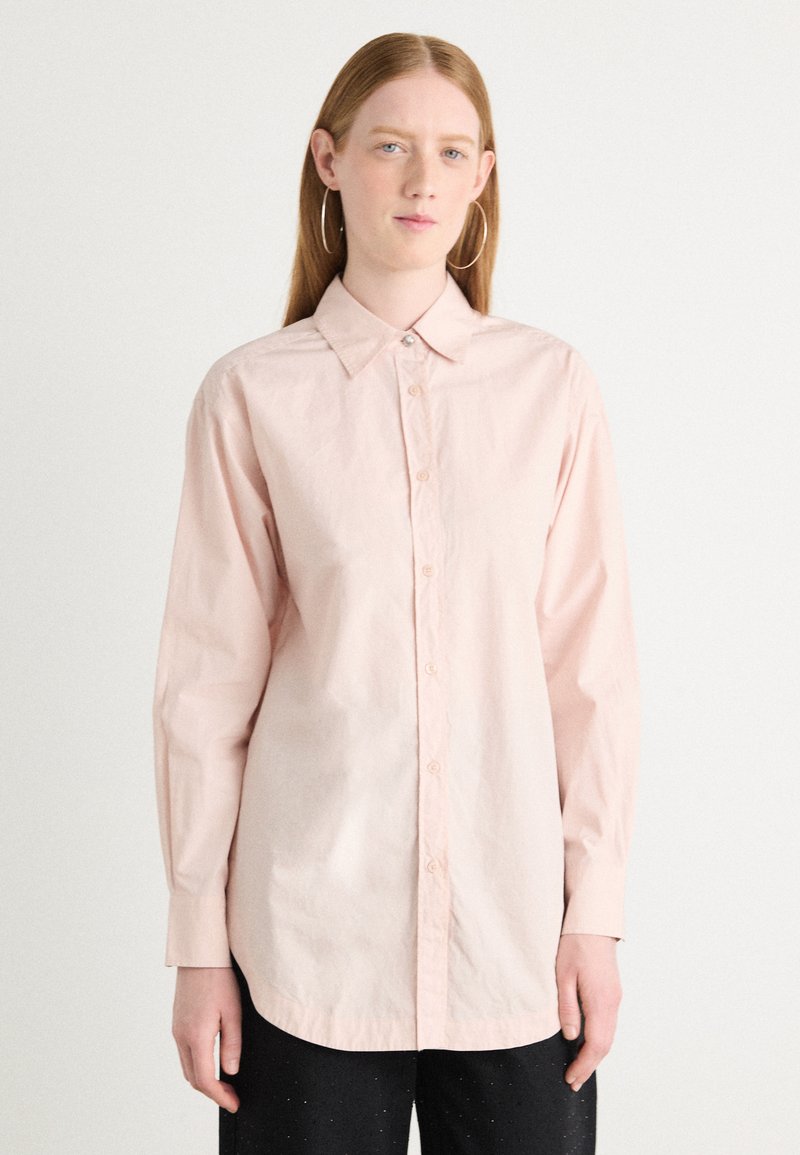 Light pink collared shirt made of soft, lightweight fabric. Features a button-down front, long sleeves, and a relaxed fit.