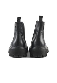 Botas de tobillo de cuero negro con paneles laterales elásticos y suelas de goma gruesas. Presentan tiradores en la parte posterior para facilitar su puesta.