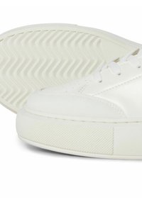 White sneaker with a smooth leather finish, flat rubber sole, round toe, and lace-up design; features textured side panel.