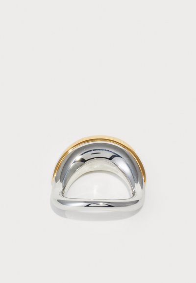 Kovový prsteň s kombinovaným dizajnom, s hornou časťou zlaté a dolnou časťou lešteného striebra, zakrivený a hladký.