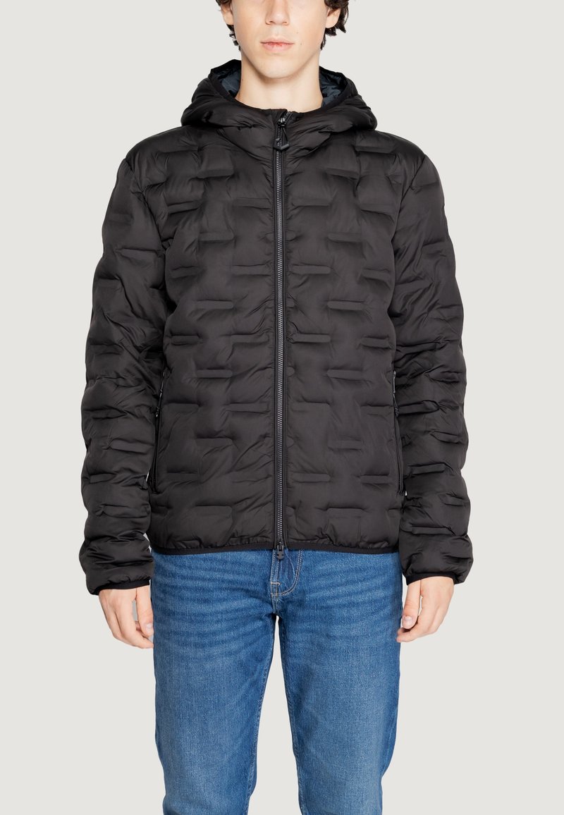 Giacca a vento nera con cappuccio, caratterizzata da una texture trapuntata, zip frontale e polsini elasticizzati. Indossata sopra jeans blu.