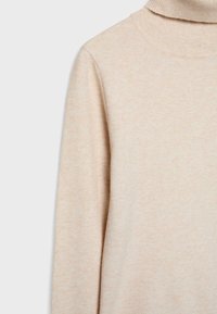 Pull beige en maille douce à col roulé avec manches longues et col fin côtelé, montré de la poitrine à la zone des épaules.