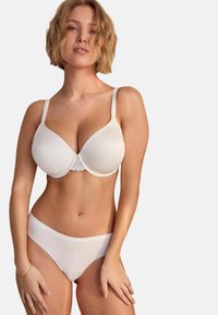 Soutien-gorge blanc avec des coques lisses et des détails en dentelle sur la bande, associé à un slip blanc uni. Les deux sont fabriqués en tissu doux et extensible.
