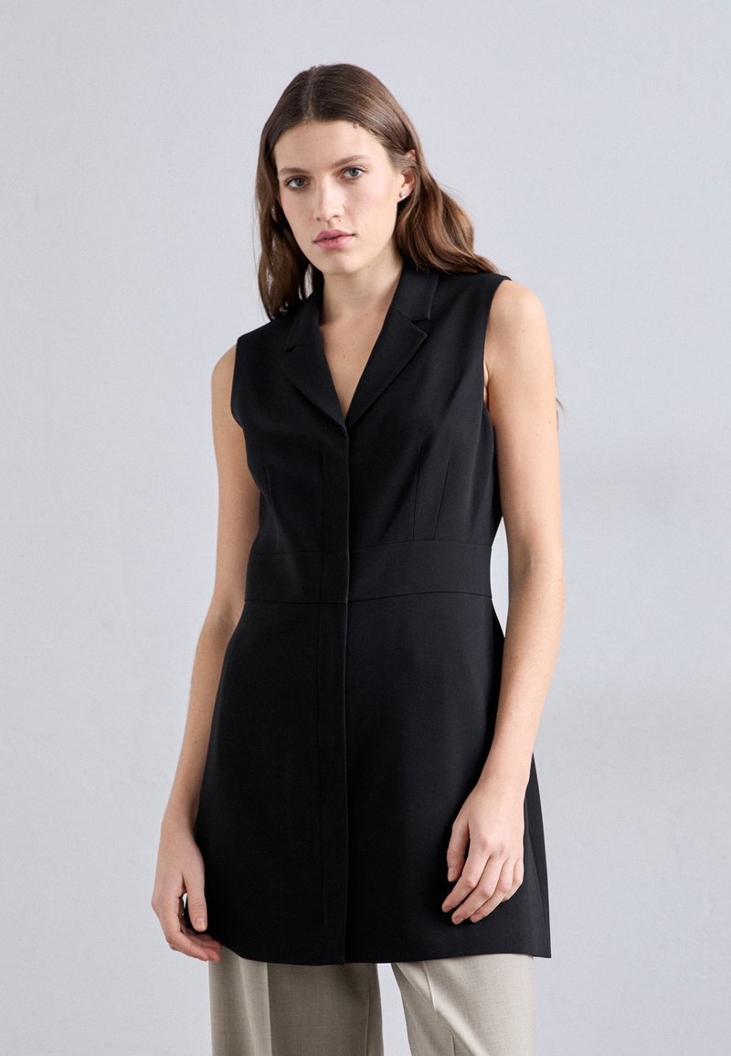 Melns bez piedurknēm kleita ar izgriezuma apkakli, strukturētu piegriezumu un vienu pogu aizdari, izgatavota no gludas auduma ar minimālistisku dizainu.