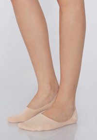Calze invisibili nude con una texture liscia, design a taglio basso e bordo elastico, che si adattano al piede senza tessuto visibile sopra la linea delle scarpe.