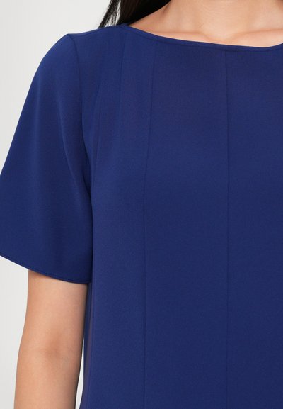 Rochie scurtă, cu mâneci scurte, de culoare albastră, realizată dintr-un material neted, cu decolteu rotund și detalii cu cusături verticale pentru un aspect curat și bine structurat.