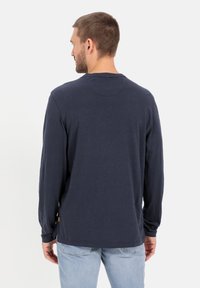 Marineblaues Langarmshirt aus weichem Stoff, mit Rundhalsausschnitt und einem dezenten Etikett am Saum. Das Design ist schlicht und klassisch.