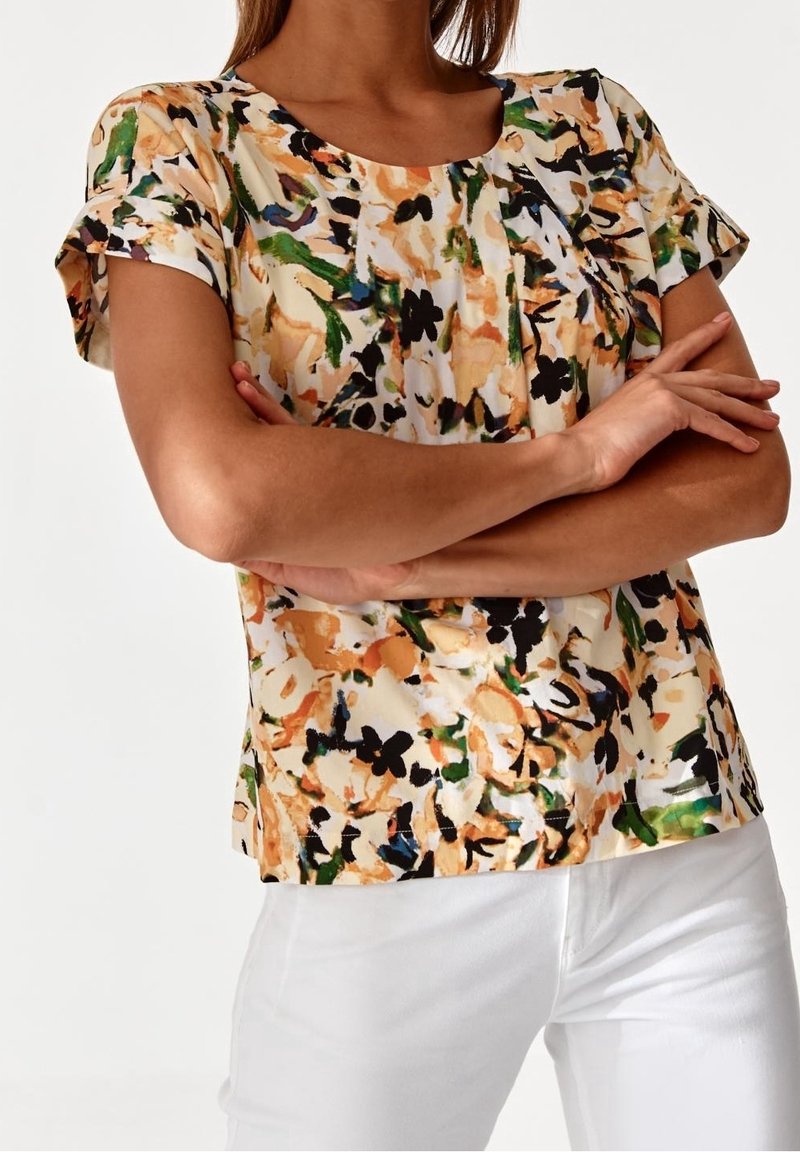 Blusa a maniche corte in una stampa astratta multicolore con tonalità di arancione, verde, nero e crema. Presenta un collo rotondo e una vestibilità rilassata.