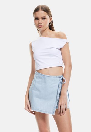 Top corto blanco sin hombros combinado con una falda envolvente de mezclilla azul clara con detalle de atado lateral. Tejido suave con un ajuste casual.