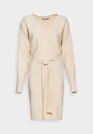 Gebreide beige wikkeljurk met V-hals, lange mouwen, geribbelde textuur en een bijpassende riem gestrikt in de taille.