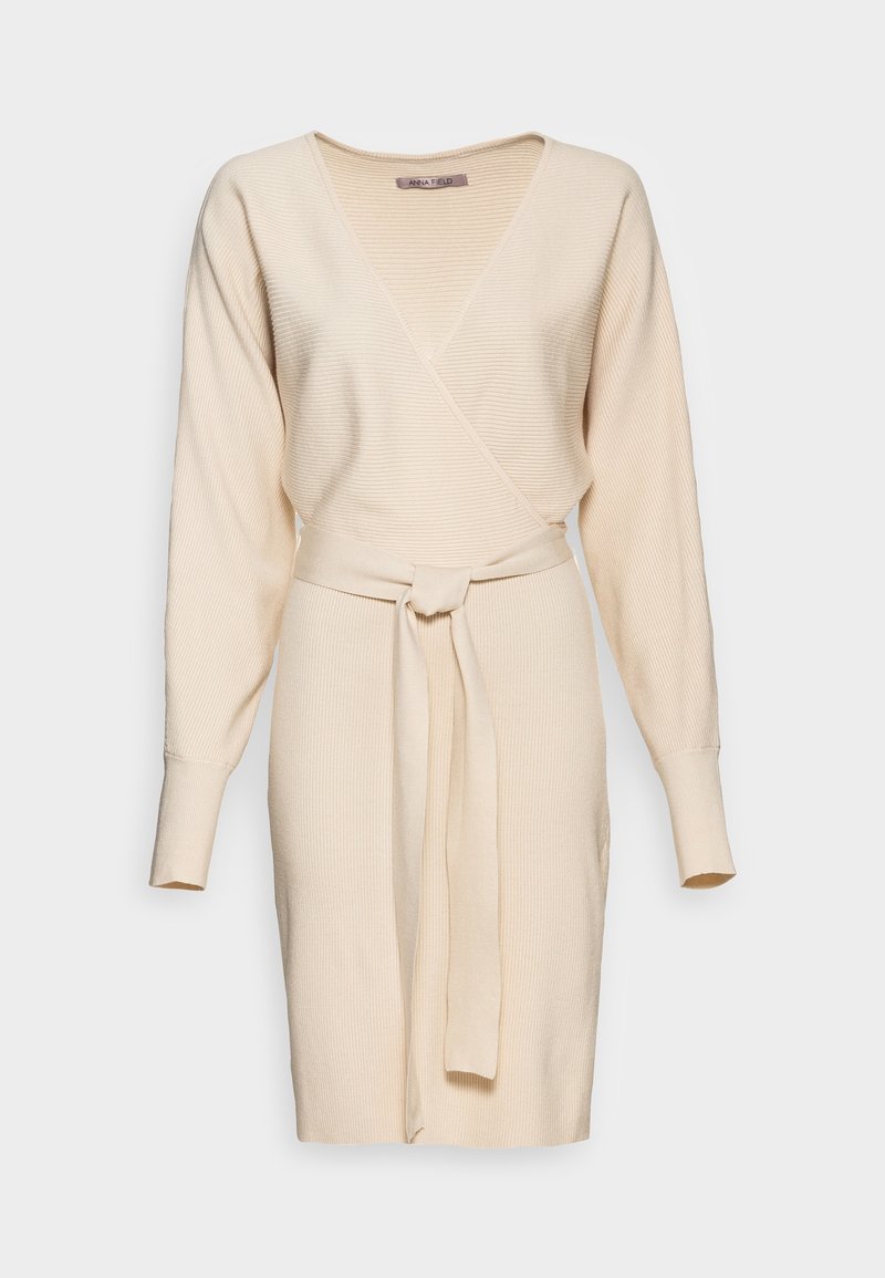 Robe portefeuille en maille beige avec col en V, manches longues, texture côtelée et ceinture assortie nouée à la taille.