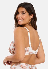 Soutien-gorge blanc à motif floral avec des bonnets rembourrés, des bretelles réglables et des finitions en dentelle, doté d'une fermeture à crochets et œillets au dos.