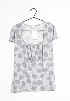 Szara bluzka krótko rękawowa z okrągłym dekoltem, z plisowanym przodem i okrągłymi szarymi wzorami na jaśniejszym szarym tle.