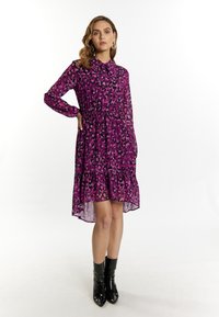 Doorzichtig paarse jurk met zwart luipaardprint, voorzien van een kraag, lange mouwen, een geraffineerde taille en een gelaagde zoom. Gecombineerd met glanzende zwarte enkellaarsjes.