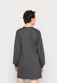 Vestido cinza de manga longa com um corte descontraído, apresentando ombros franzidos, decote redondo e tecido suave, caindo até a metade da coxa.