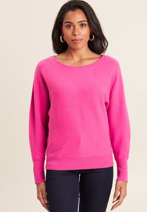 Bright pink sweater with a wide neckline and long, slightly puffed sleeves. Ribbed hem and cuffs. Soft texture. Paired with dark pants.