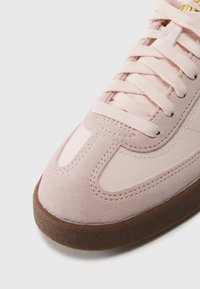 Ljusrosa sneakers med en kombination av mocka och textil, rund tå, platta skosnören och en sula av gummigummi för bra grepp.