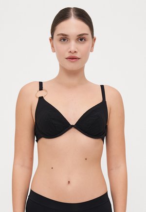 Reggiseno nero con un design testurizzato geometrico, supporto with ferretto e spalline regolabili. Presenta un accento circolare dorato su una delle spalline.