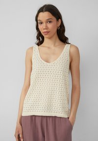 Ivore gebreide tanktop met V-hals, opengewerkte patroon en geribbelde onderrand, gecombineerd met losse, gestructureerde rozenkleurige broek.