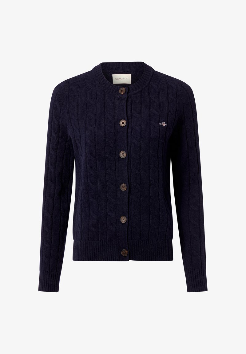 Gilet en tricot torsadé bleu marine en tissu doux, avec un col rond, cinq boutons marron et un logo discret sur la poitrine.