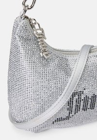 Sudraba rokassoma, kas dekorēta ar maziem rhinestone akmeņiem, ar gludu auduma apdari un metāla rāmi ar ķēdes akcentiem. Apaļa forma.