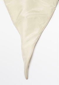 Cremefarvet silkescarf med en trekantet form, der har en glat tekstur og delikate stikninger langs kanterne, der taperer til en spids spids.