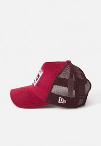 Rød corduroy baseballcap med mesh bag. Har et logo patch på forsiden, buet skygge og justerbar rem. Tekstureret stofdetalje.