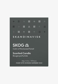 Scented candle package with a dark gray background, white text, and geometric patterns. Labels include "SKOG" and details about material and burn time.