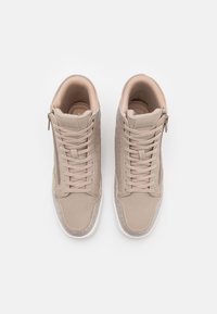 Světlé béžové vysoké tenisky s texturovanými panely, šněrováním vpředu, zipovým uzávěrem a bílými gumovými podrážkami s nenápadnými akcenty.