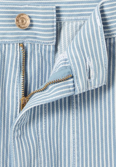 Tissu en denim rayé bleu clair et blanc avec une fermeture éclair dorée et un bouton. Présente des coutures classiques et des détails à bords bruts.
